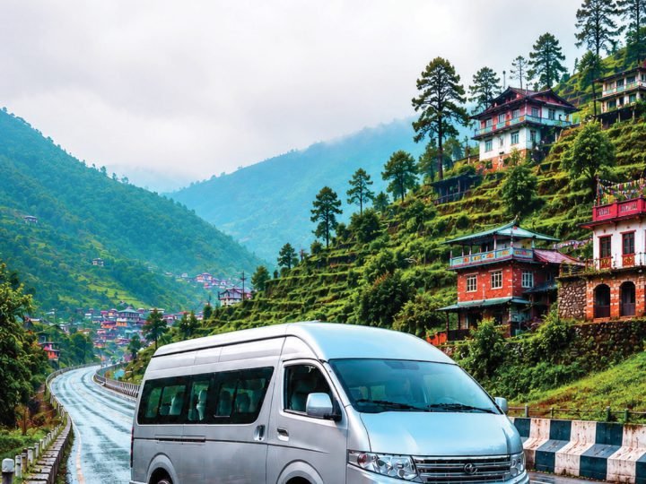Silver electric van on a wet hill road lined with traditional houses
