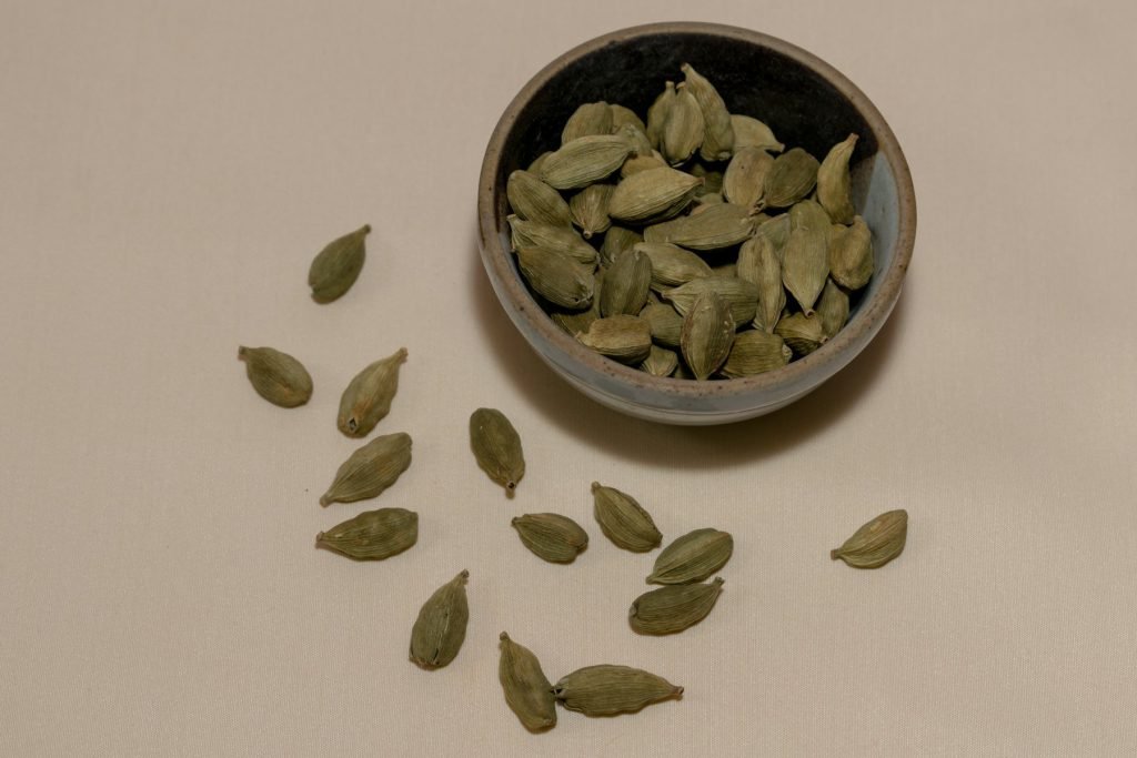 Green cardamom pods in and around a small bowl